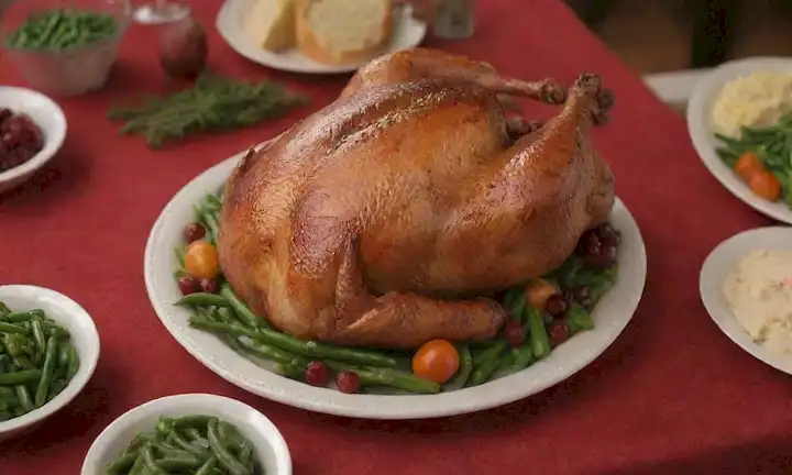 Un pavo tostado cálido y dorado (Pavo asado) en un vibrante mantel rojo y verde, rodeado de alimentos festivos, como puré de papas, frijoles verdes almandina y salsa de arándano, con una guirnalda decorativa o una pieza central que añade un pop de color
