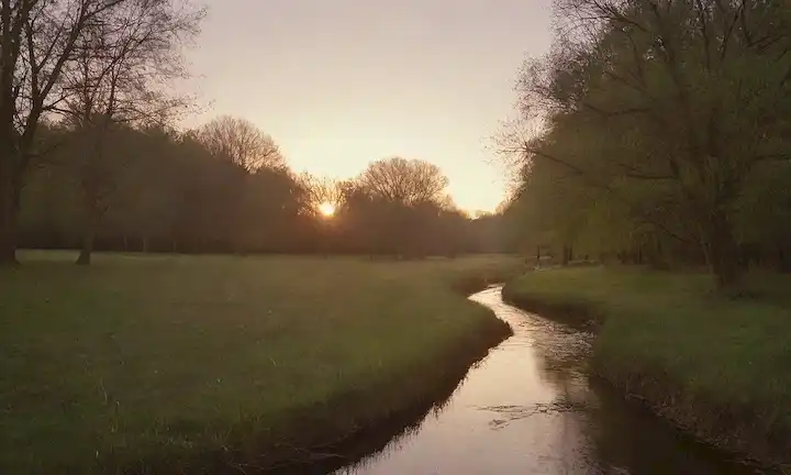 Un paisaje tranquilo y sereno con una puesta de sol tranquila, iluminación suave, una suave corriente que fluye en primer plano, unos pocos árboles que se balancean suavemente en la brisa, un ambiente cálido y acogedor