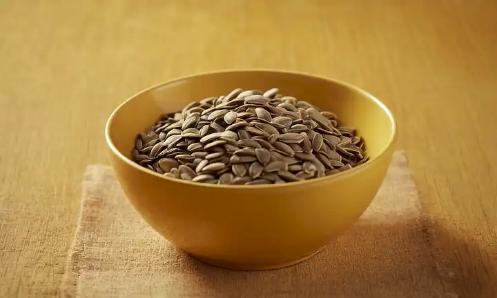 Fondo caliente, semillas de girasol en un tazón o plato, persona relajada y feliz, iluminación suave, texturas naturales, colores sanos, atmósfera relajante, sombras sutiles