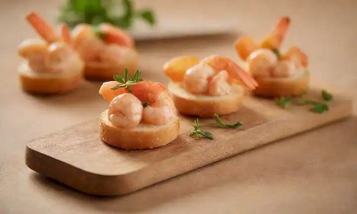canapés de langostino dorado en una tabla de madera rústica, adornado con virutas boniato y hierbas frescas, con un fondo cálido y color beige, con un enfoque suave para destacar las texturas y los colores del plato, rodeado de delicados utensilios artesanales