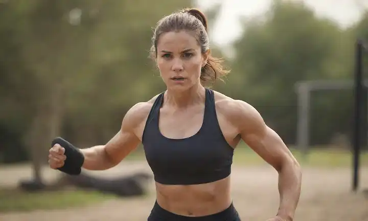 Un atleta en acción, con desgaste atlético, con una expresión determinada, en un fondo natural, rodeado de equipos de fitness, mostrando flexibilidad y fuerza, con sutiles momentos y sombras