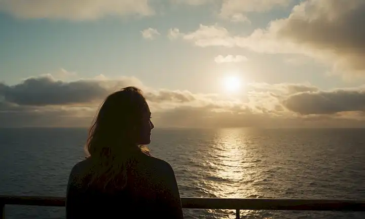 Una persona rodeada de nubes con sombras oscuras, un mar tranquilo o océano en el fondo, un sol suave que se levanta detrás de las nubes, una sonrisa sutil en su rostro, y un sentido de esperanza