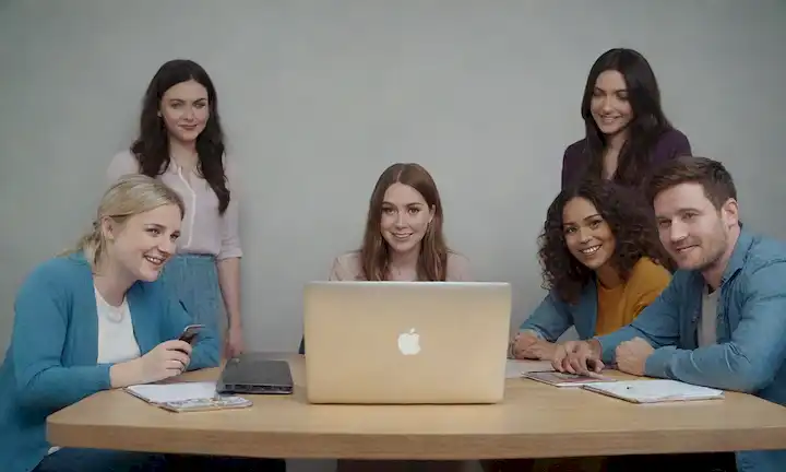 Un grupo de personas se reunieron alrededor de una mesa con ordenadores portátiles y teléfonos, algunos sonriendo, otros mirando preocupados; un fondo sutil gradiente evocando sentimientos de curiosidad, iconos de redes sociales esparcidos alrededor; una mezcla de colores brillantes y tonos mudos para transmitir amistad y precaución