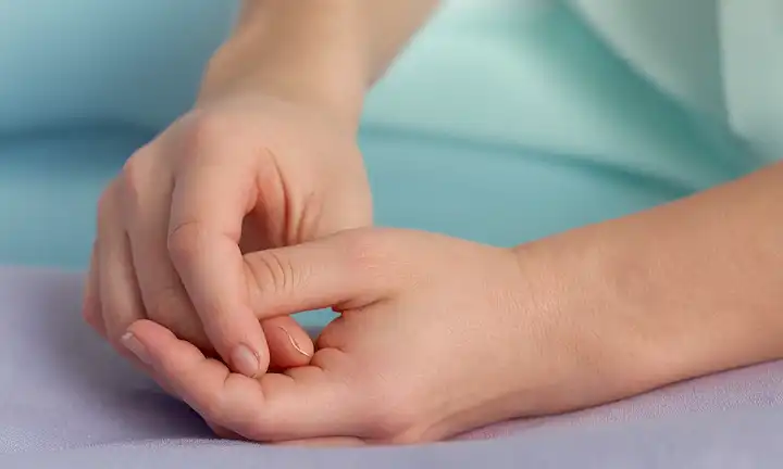 Manos suaves que anhelan una muñeca tierna, enfoque suave en la sutileza, tonalidades de fondo calmantes como el cielo azul o el mauve, un toque de atmósfera defectuosa, patrones florales delicados en el primer plano, luz natural caliente filtrando a través