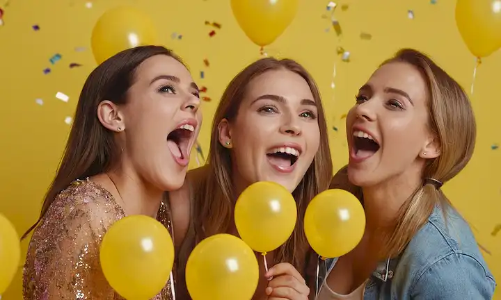 3 personas riéndose junto con bocas abiertas, rodeadas de globos coloridos y confeti, un fondo amarillo brillante, personajes de dibujos animados en las esquinas, un sentido de alegría y juguetón, un ambiente de fiesta
