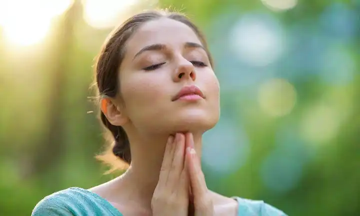 Una persona rodeada de luz sutil y brillante; las manos extendidas en un gesto suave; los ojos cerrados con una expresión suave y pacífica; elementos de la naturaleza que se mezclan con el fondo, transmiten armonía y equilibrio; enfoque suave para enfatizar los temas del mundo interior; colores calmantes como azul o verde dominante