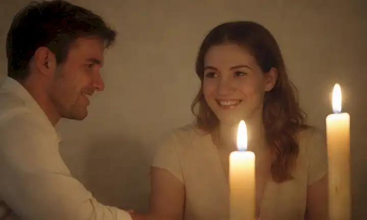 3 personas sentadas en un círculo, manos retenidas, sonriendo, ojos cerrados, velas encendidas, fondo serena, iluminación sutil, colores naturales, atmósfera íntima