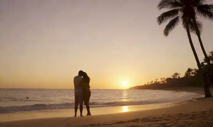 Una puesta de sol de playa serena con dos pares de siluetas abrasadoras