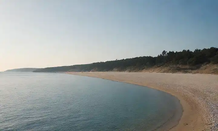 Un paisaje costero sereno con un mar tranquilo, playa de arena y barcos distantes, con colores azules y blancos suaves, iluminación cálida y suaves olas