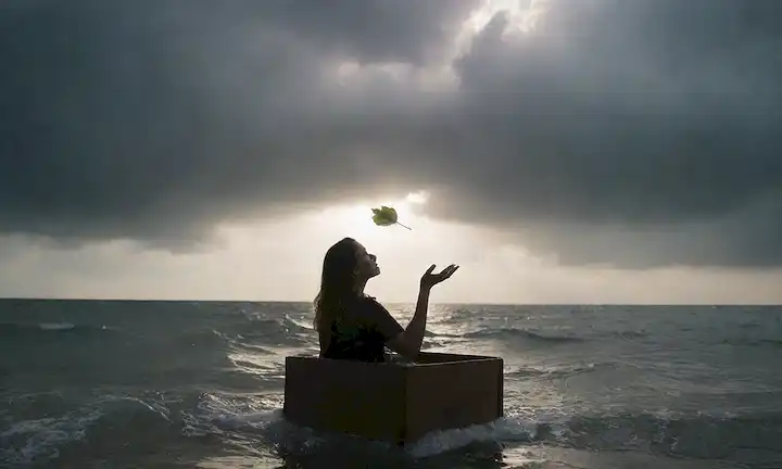 Una persona sentada tranquilamente en medio de un fondo tormentoso con burbujas de pensamiento escapando, nubes que se alejan, y un sol mirando a través; las manos liberando una hoja flotando hacia arriba, o una ola lavando sobre aguas turbulentas; un par de alas brotando de hombros, o una llave desbloqueando una caja cerrada