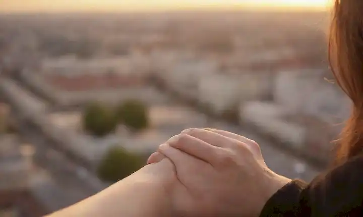 Una fotografía de tono cálido de una persona que abraza su propio brazo