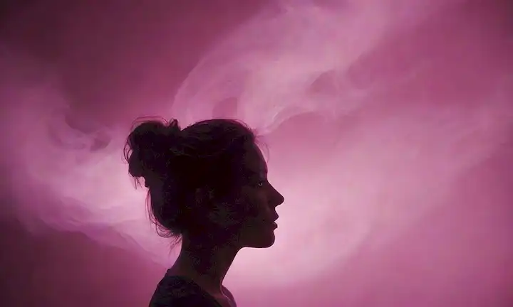 formas abstractas 3D, colores púrpuras y rosas giratorios, una silueta de una persona en el pensamiento, senderos de humo brillante, sutiles toques de iconos tecnológicos, brillantes chispas, y enfoque suave para transmitir creatividad y liberación