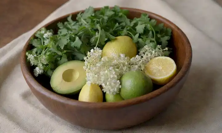 raíces de perejil fresco con hojas verdes y flores blancas en un tazón de madera rústica, rodeado de limones rebanados, aguacates y verdes mezclados en un mantel de lino, luz natural suave iluminando la escena, tonos terrenales con pops de color brillante