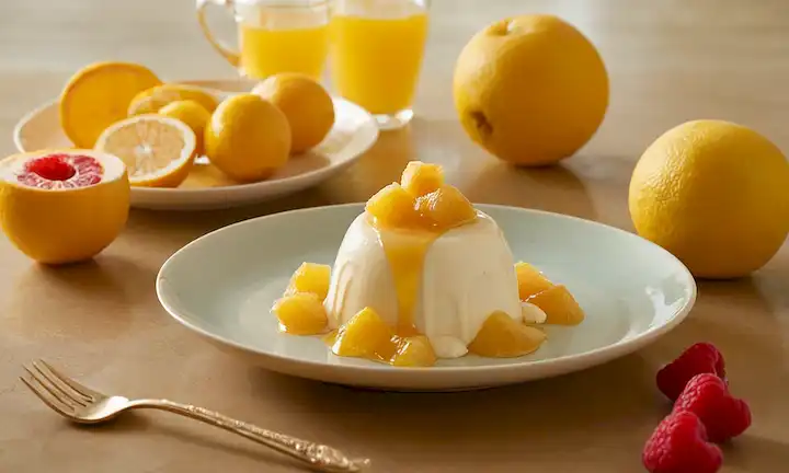 chirimoyas maduras con goteo de zumo dulce, una cuchara dorada sacando la pulpa, un fondo de la luz del sol caliente, un plato con rebanadas de fruta fresca y postre cremoso, un toque de un mostrador de cocina con utensilios, un sutil gradiente de colores pastel, un ambiente acogedor que evoca sentidos